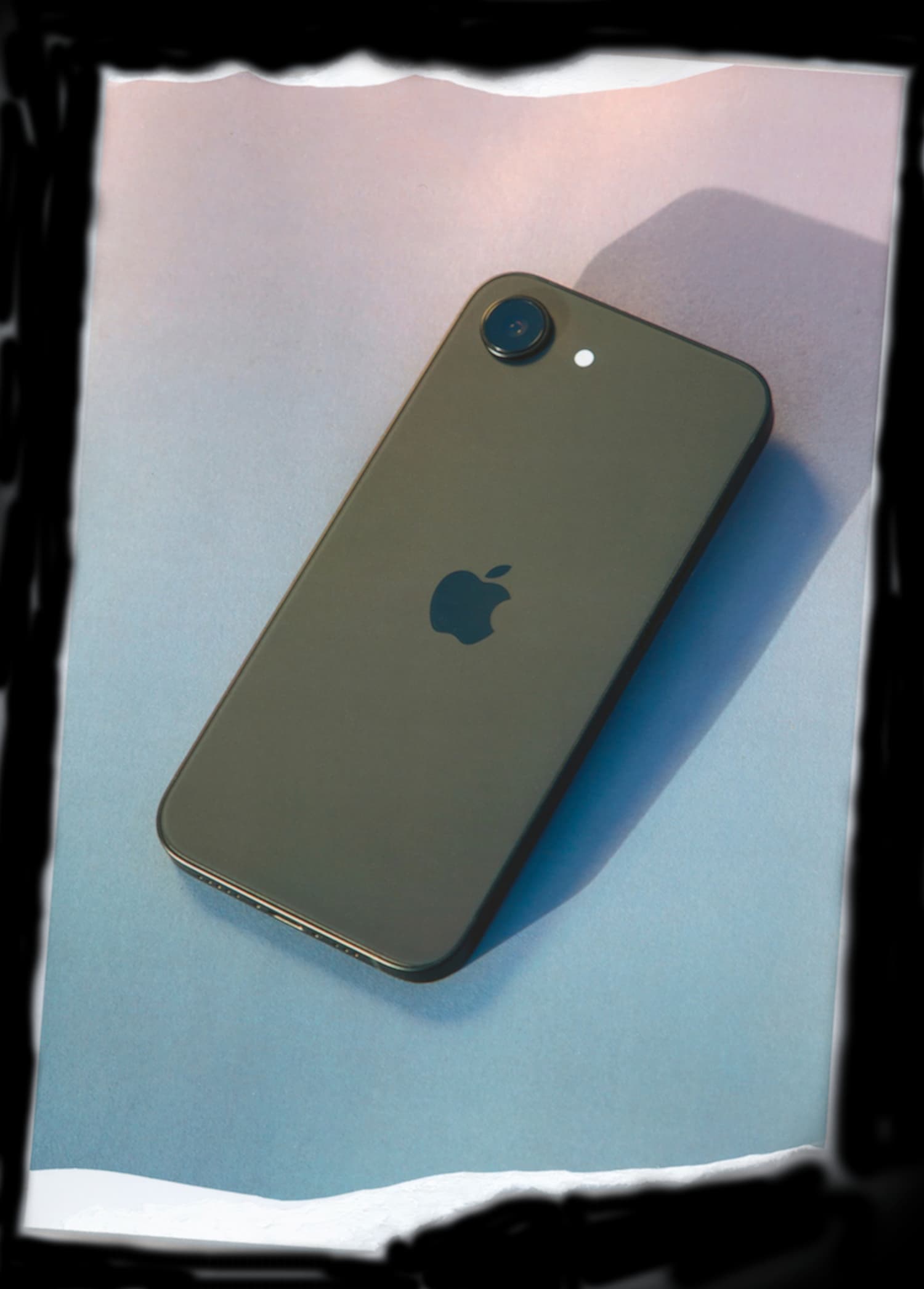 An iPhone placed on a paper background with a torn edge.